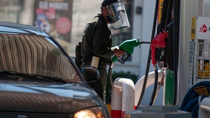 Un hombre atiende a un cliente dentro de una gasolinera, el precio del combustible aumentará a partir de este primero de enero.